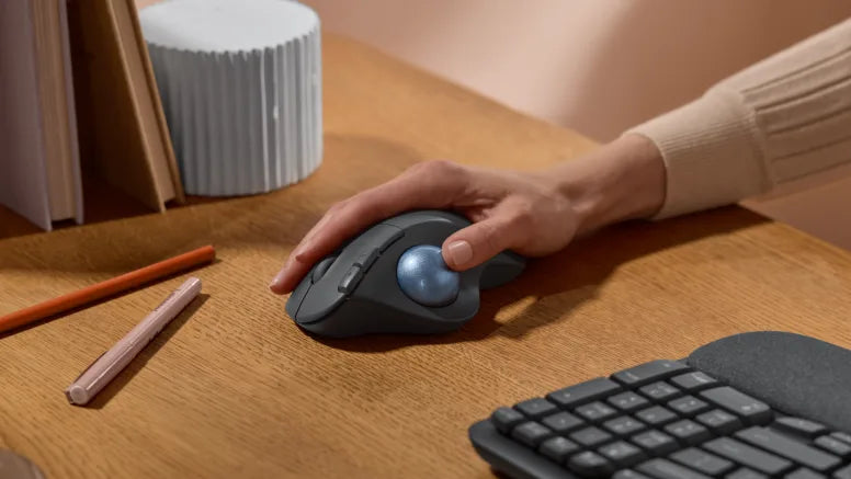 Ergonomic trackball mouse on wooden desk with mechanical keyboard and pencils for productive workspace setup