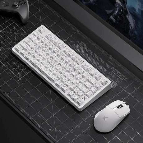 White mechanical keyboard and matching mouse on grid desk mat, gaming setup with controller and monitor